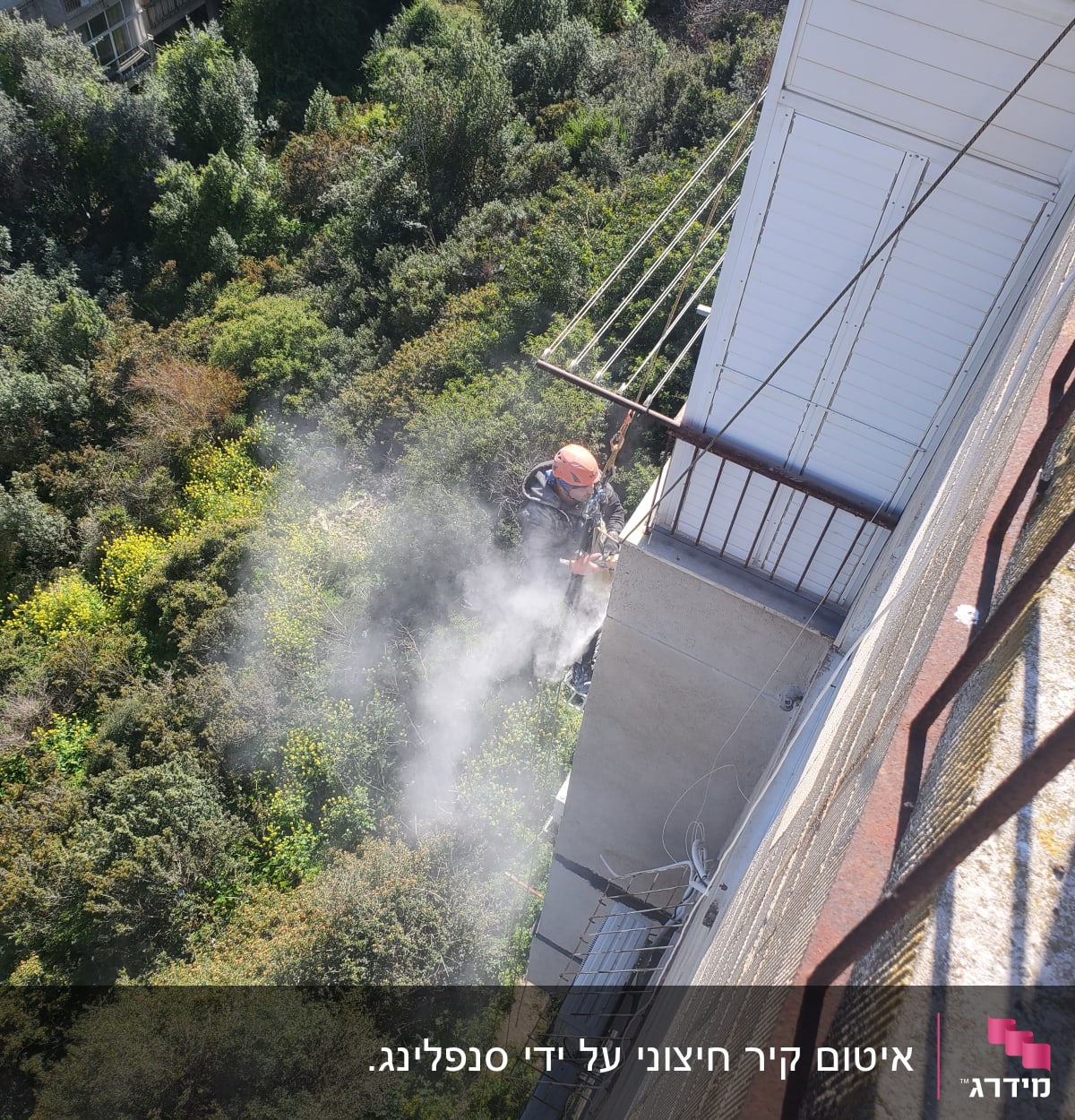 אדם עם קסדה עובד על איטום קיר חיצוני